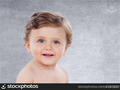 Baby with one years old doing funny gestures on a grey background