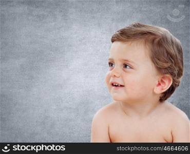 Baby with one years old doing funny gestures on a grey background