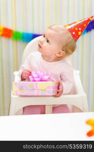 Baby with present looking in corner