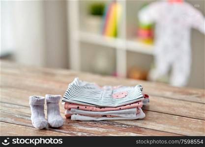 babyhood and clothing concept - baby clothes on wooden table at home. baby clothes on wooden table at home