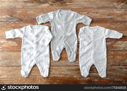 babyhood and clothing concept - baby clothes set of bodysuits and socks on wooden table. baby clothes set of bodysuits on wooden table