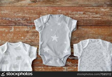 babyhood and clothing concept - baby clothes set of bodysuits and socks on wooden table. baby clothes set of bodysuits on wooden table