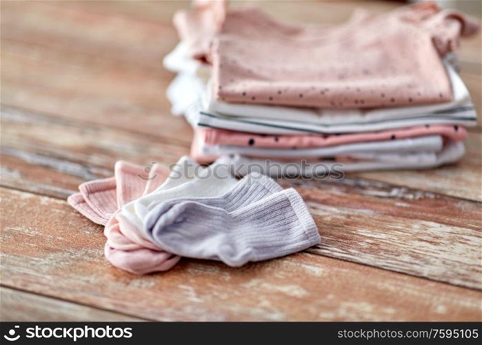 babyhood and clothing concept - close up of baby clothes on wooden table. close up of baby clothes on wooden table