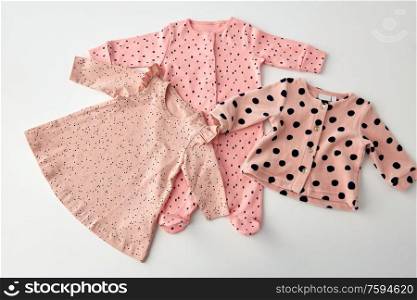 babyhood and clothing concept - pink clothes for baby girl with dot print on white background. pink clothes for baby girl on white background