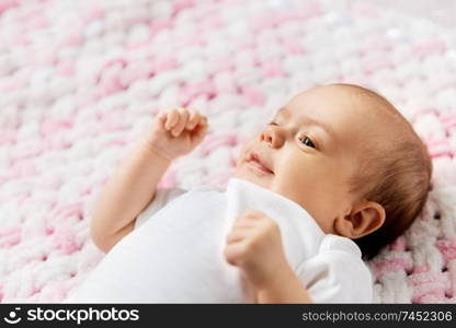 babyhood and people concept - sweet little baby girl lying on knitted pink blanket of plush yarn. sweet baby girl lying on knitted plush blanket
