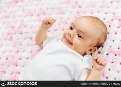 babyhood and people concept - sweet little baby girl lying on knitted pink blanket of plush yarn. sweet baby girl lying on knitted plush blanket