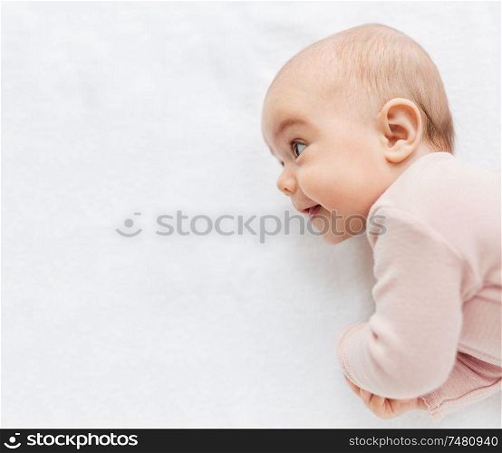 babyhood and people concept - sweet little baby girl lying on white blanket. sweet baby girl lying on white blanket
