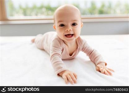 babyhood and people concept - sweet little baby girl lying on white blanket. sweet baby girl lying on white blanket