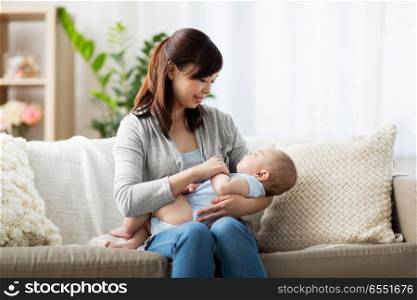 babyhood, childhood and people concept - asian mother holding sleeping baby boy at home. happy asian mother holding sleeping baby boy. happy asian mother holding sleeping baby boy