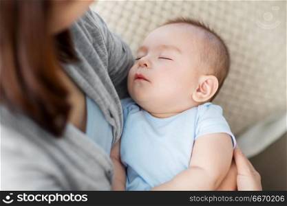 babyhood, childhood and people concept - close up of mother holding sleeping asian baby boy. close up of mother holding sleeping asian baby boy. close up of mother holding sleeping asian baby boy