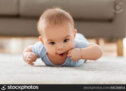 babyhood, childhood and people concept - sweet little asian baby boy lying on floor at home. sweet little asian baby boy lying on floor at home