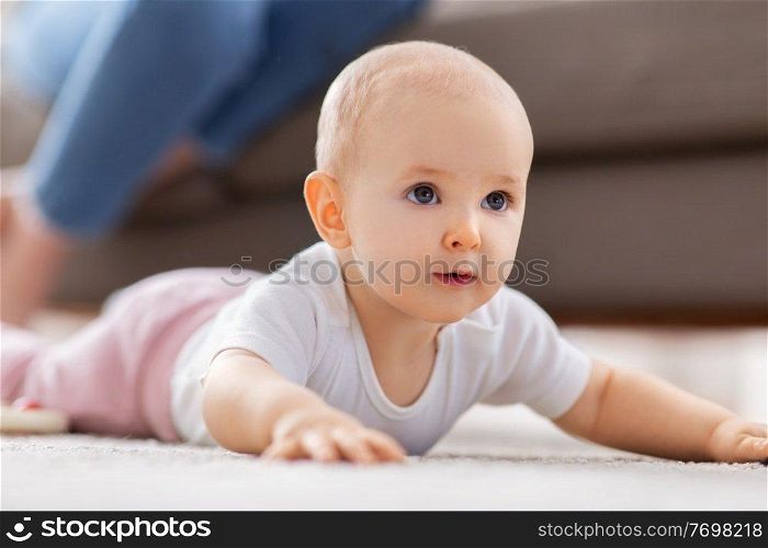 babyhood, children and people concept - little baby girl crawling on floor at home. little baby girl crawling on floor at home