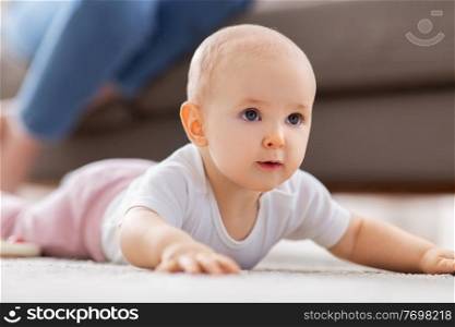 babyhood, children and people concept - little baby girl crawling on floor at home. little baby girl crawling on floor at home