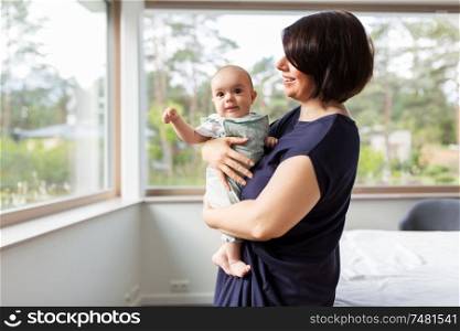 babyhood, motherhood and people concept - happy middle-aged mother holding baby daughter at home. middle-aged mother holding baby daughter at home