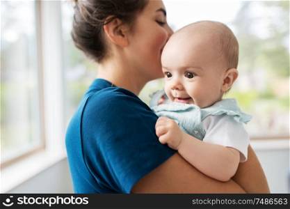 babyhood, motherhood and people concept - mother holding baby daughter at home. mother holding baby daughter at home