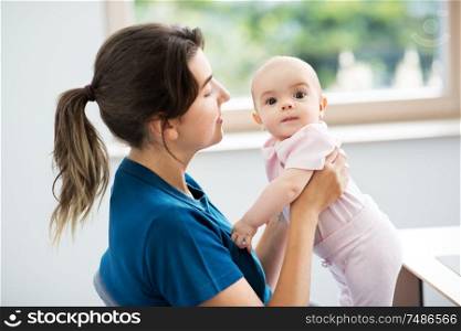 babyhood, motherhood and people concept - mother holding baby daughter at home. mother holding baby daughter at home