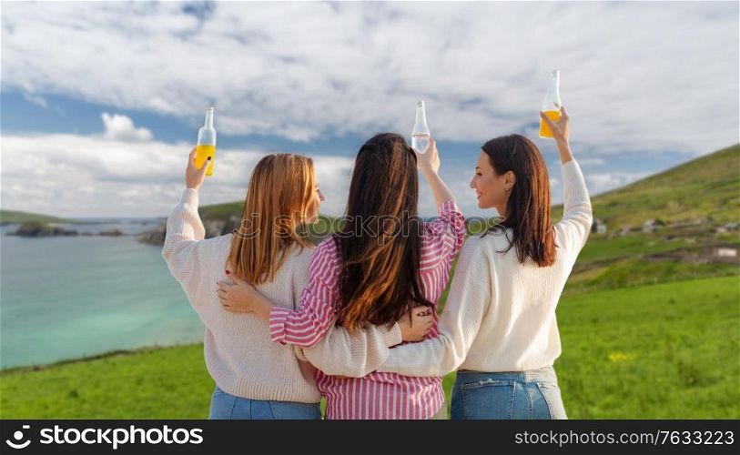bachelorette party, friendship and travel concept - group of happy young women or female friends toasting non alcoholic drinks over ireland on background. women toasting non alcoholic drinks in ireland