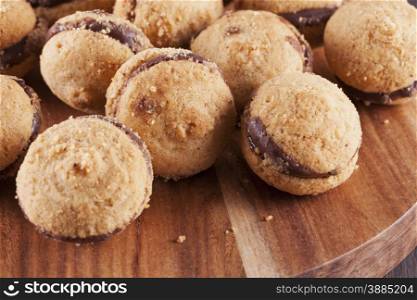 Baci di dama biscuits over round chopping board, close up, horizontal image