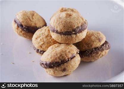 Baci di dama biscuits over white stand, wooden background, horizontal image