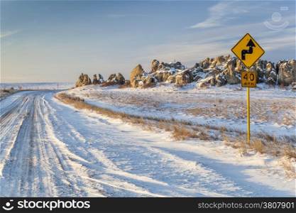 back country road over prairie at Natural Fort in northern Colorado in winter scenery, a road sign with bullet holes