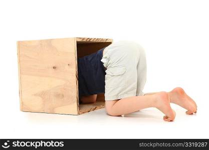 Back end of seven year old boy sticking out of wooden box over white background.