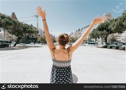 Back of a woman celebrating in the main plaza of porto, Oporto, during a super sunny day, relax and holiday concept, hot day, summer, dress