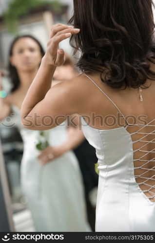 Back of African-American woman in evening gown looking at mirror.