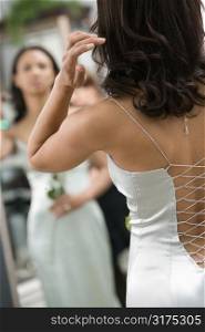 Back of African-American woman in evening gown looking at mirror.