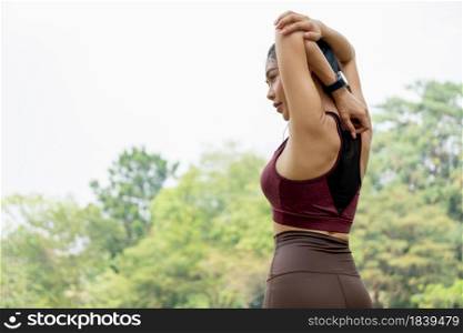 Back of Sport woman do arm and back stretching in park or garden and she look to left side with day light.