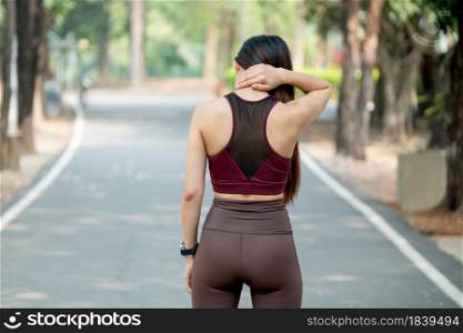 Back of sport woman touch her neck for action of pain after exercise in park or garden during morning.