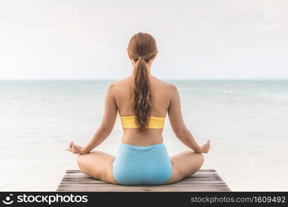 Back of views woman practice yoga lotus pose to meditation summer vacation on pier with sea beach feeling so happiness and cheerful,Travel in tropical beach Thailand,vacations and relaxation Concept