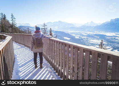 Back of young woman who is raising her hands on the mountain, outlook. Gaisberg, Austria