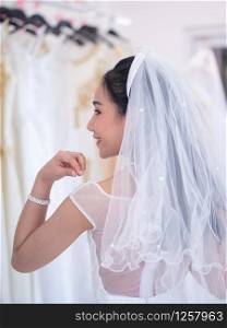 Back shot of asian bride checking her dress in dressing room.