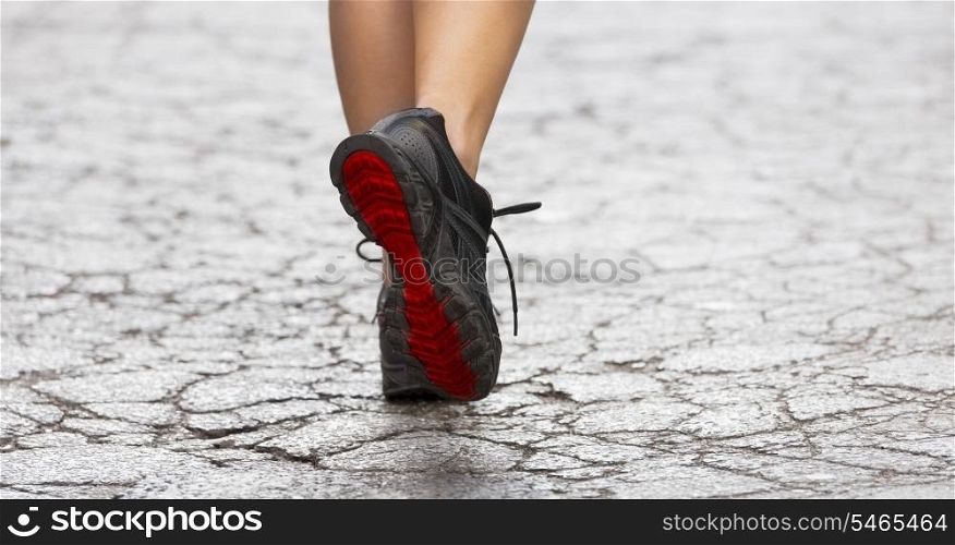 back shot of young lady with fitness old shoes in act to walking ,running on a broken fashion road .