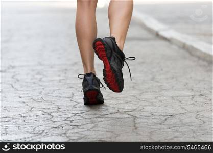 back shot of young lady with fitness shoes running on cracked road . USED SHOES