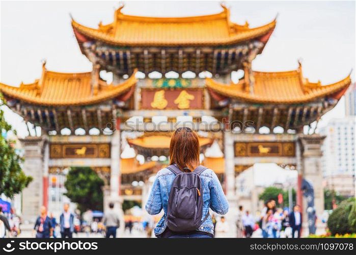 Back side of asian backpacker woman looking and sightseeing when travelling over the Jinbi square, Kunming, China, travel and tourism, china culture and traditional, famous place and landmark concept