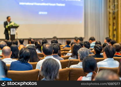 Back side of audience listening the Speaker with podium on the stage in the conference hall, business and education concept