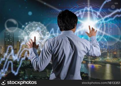 Back side of Businessman working with modern virtual screen technologies over the Trading graph on the cityscape at night background, Business financial and technology concept