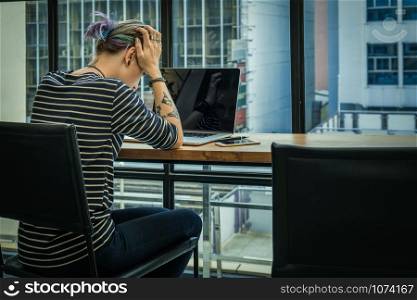 Back side of Depressed Hipster young Woman freelancer thinking about her job in serious action which have technology Laptop in the Loft cafe workplace. Creative Startup and entrepreneur business concept