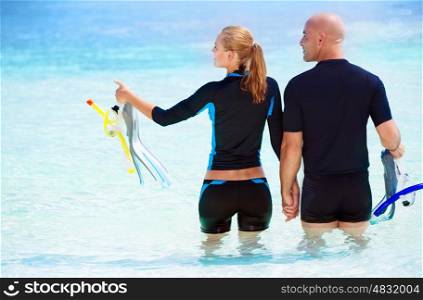 Back side of happy diver couple standing in the water and with wonder looking on side, enjoying extreme sport and active summer vacation