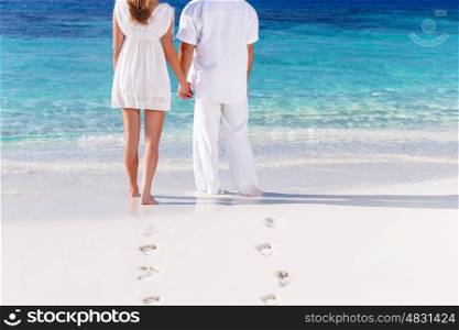Back side of young couple standing on the white sandy beach and looking on the sea, body part, togetherness concept