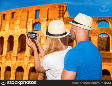 Back side of young happy couple taking picture of beautiful gorgeous ancient Coliseum, honeymoon vacation in Rome, Italy, Europe