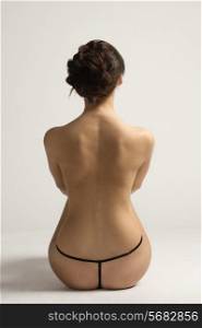 back side shot of nude and pretty woman with dark hair. she is in artistic pose. natural skin retouch.