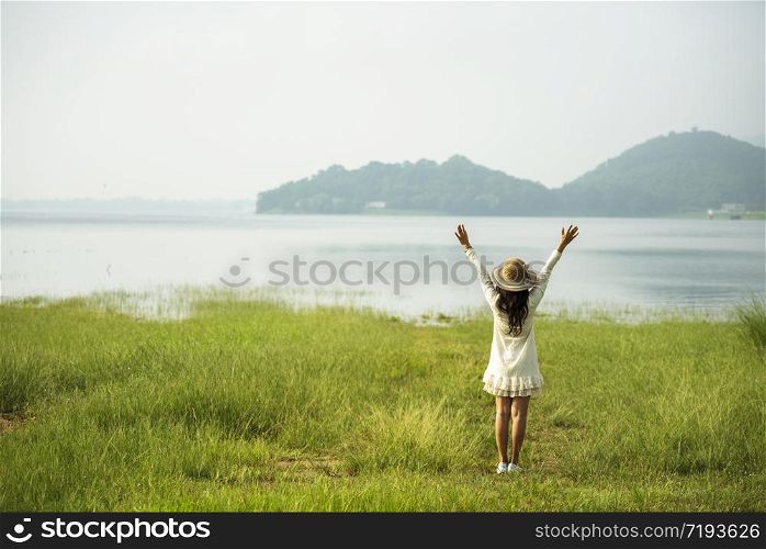 Back side woman feeling fresh freedom positive energy standing grass field flower meadow international woman&rsquo;s day 8 march. Cheerful morning relaxation springtime mountain view with sunlight