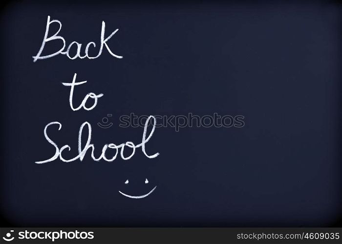 Back to school background, conceptual phrase with drawing of a smiley face on the blackboard, beginning of educational season