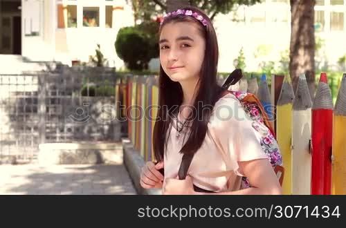 Back to school - beautiful young schoolgirl in front of the school, education concept.