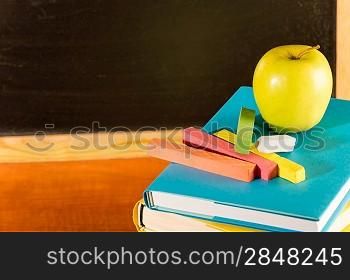 Back to school books and apple, colorful chalks and board