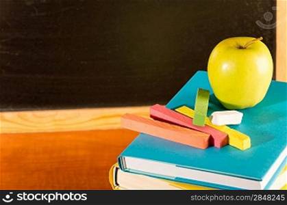 Back to school books and apple, colorful chalks and board