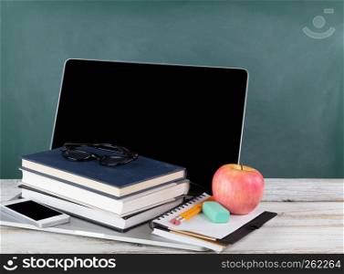 Back to school concept consisting of technology and traditional stationery with green chalkboard
