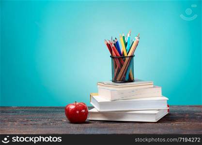 Back to School concept.School Books, colored pencils and apple on blue background. Back to School concept. Books, colored pencils and apple
